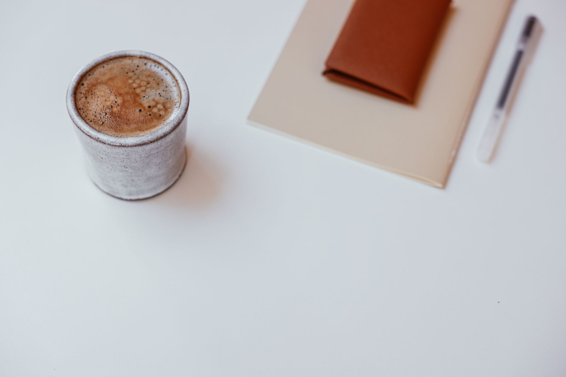 Kaffekop og notesbog på et lyst skrivebord